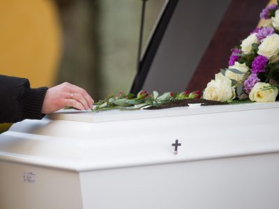 A closeup shot of a person hand on a casket with a blurred background